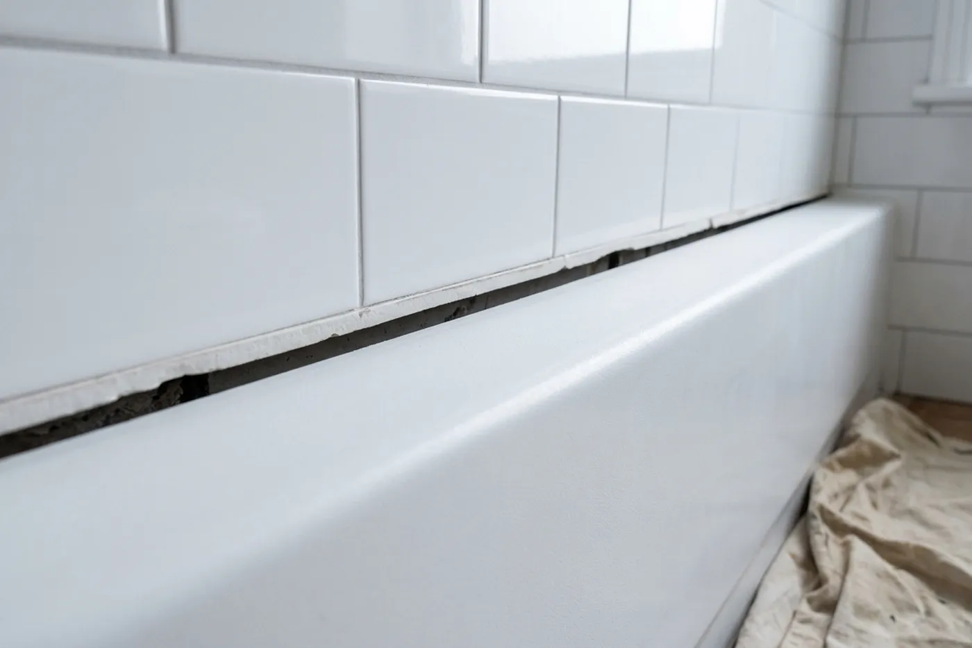 A bath to tile joint stripped back to a bare, open gap between the tile edge and the bath, clean and dry before resealing