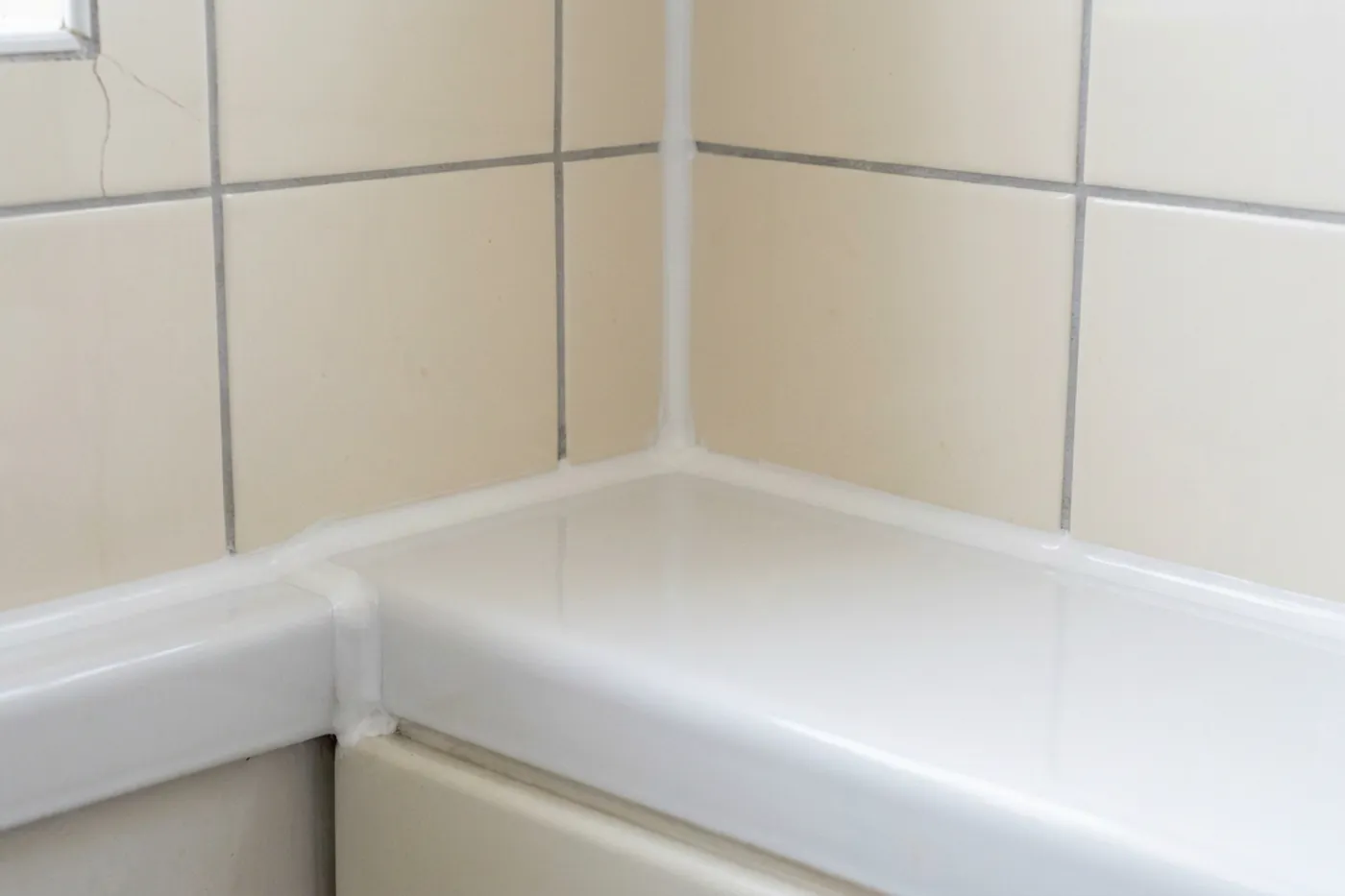 The same bath joint from the same position after resealing, carrying a clean, evenly tooled white silicone bead